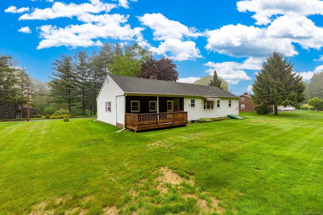 back of property with a deck and a yard
