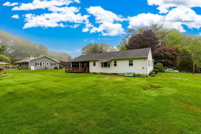 back of house featuring a wooden deck, a yard, and a chimney