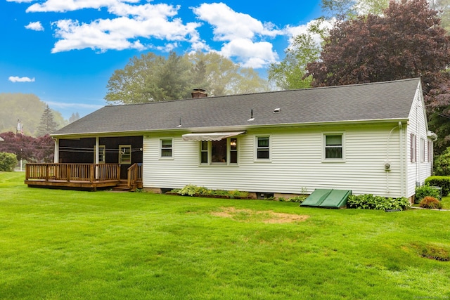 back of property with a lawn, a deck, and a chimney