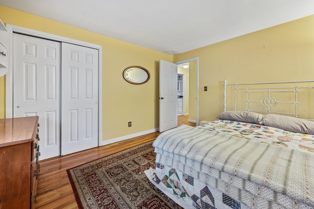 bedroom featuring wood finished floors, baseboards, and a closet