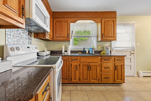 kitchen with white appliances, a sink, brown cabinets, and light tile patterned floors
