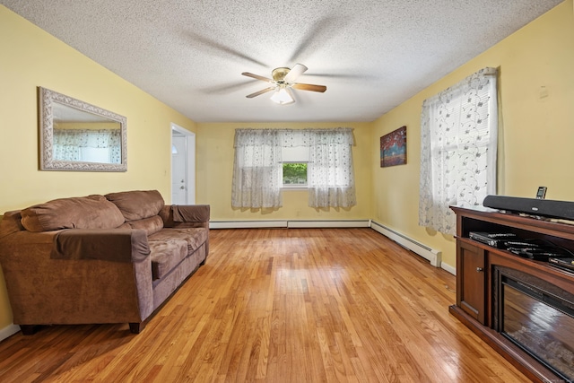 living room featuring light wood-style flooring, ceiling fan, a baseboard heating unit, a baseboard radiator, and a textured ceiling