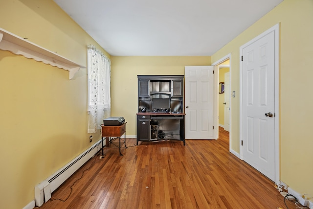 bedroom featuring baseboard heating, hardwood / wood-style flooring, and baseboards