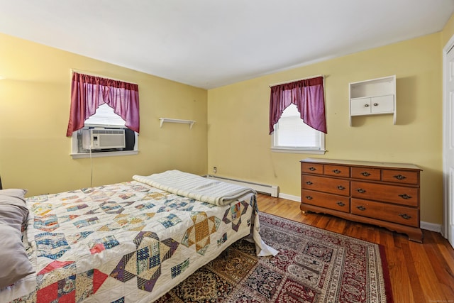 bedroom featuring a baseboard heating unit, cooling unit, wood finished floors, and baseboards
