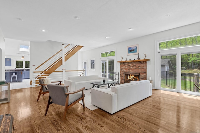 20A Bush Hill Dr, East Lyme, CT 06357 - living room with wood finished floors, stairs, a brick fireplace, and recessed lighting
