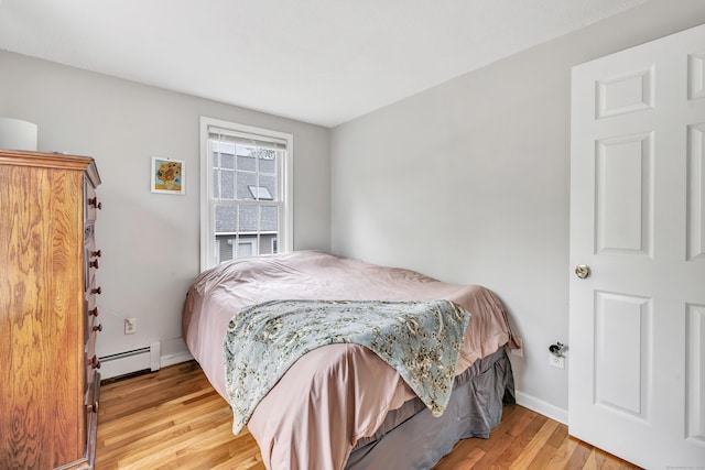 bedroom featuring wood finished floors, baseboard heating, and baseboards