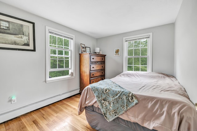 bedroom with baseboard heating and wood finished floors