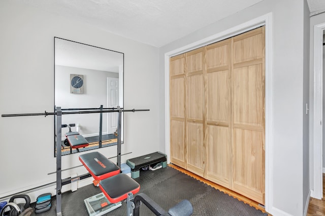exercise room featuring baseboards and wood finished floors
