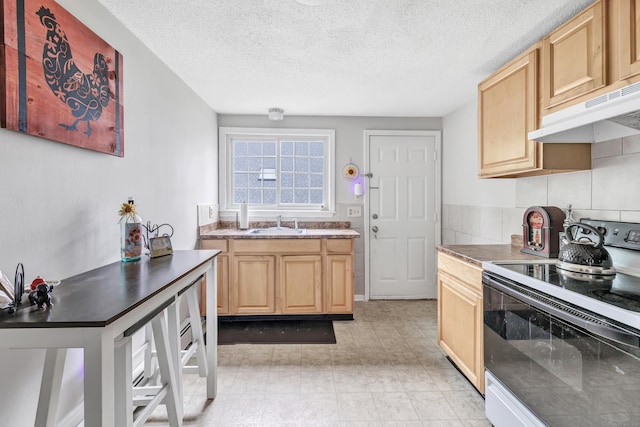 kitchen with range with electric stovetop, under cabinet range hood, light brown cabinets, a sink, and a textured ceiling
