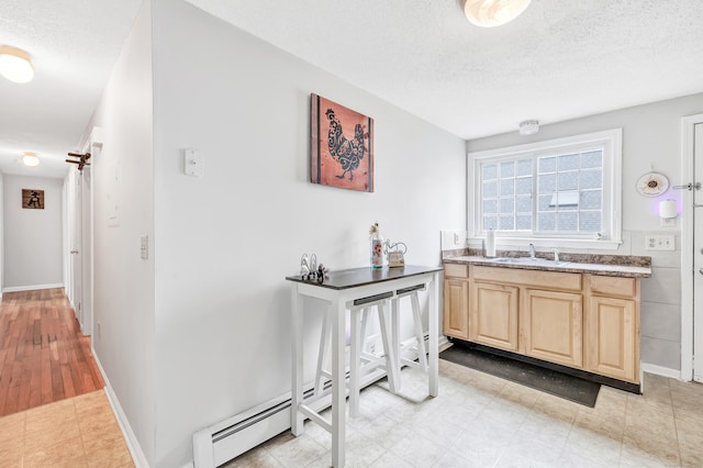 bathroom featuring a textured ceiling, baseboards, vanity, and a baseboard heating unit