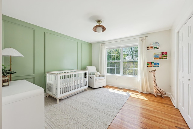 2 Red Fox Run, Wolcott, CT 06716 - bedroom featuring a decorative wall, light wood finished floors, a closet, a nursery area, and baseboards