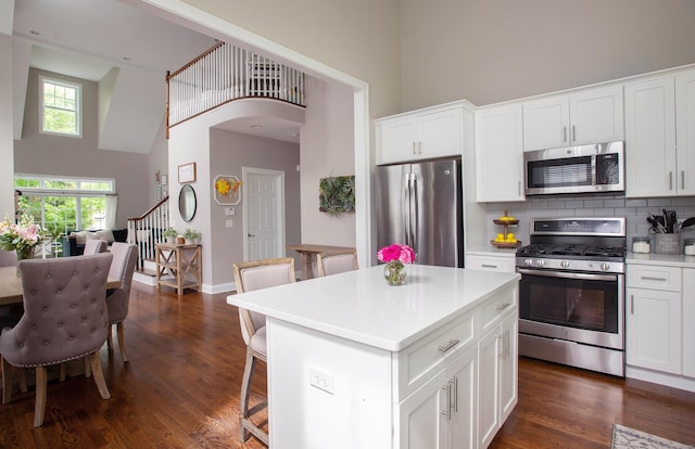 78 Copper Square Dr Unit 78, Bethel, CT 06801 - kitchen with appliances with stainless steel finishes, a high ceiling, dark wood finished floors, white cabinetry, and a breakfast bar