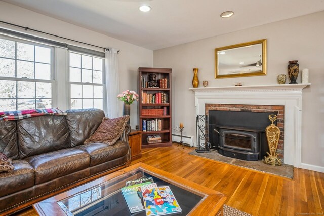 90 Akbar Rd, Stamford, CT 06902 - living area featuring a baseboard radiator, a wood stove, recessed lighting, and wood finished floors
