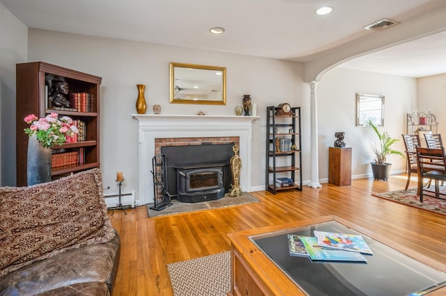 90 Akbar Rd, Stamford, CT 06902 - living room with a baseboard heating unit, ornate columns, wood finished floors, arched walkways, and recessed lighting
