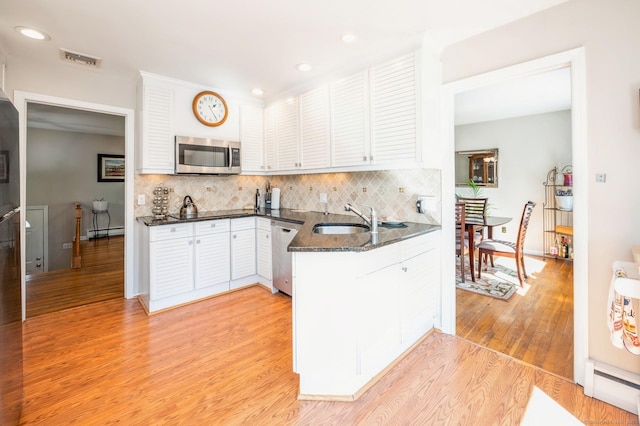 90 Akbar Rd, Stamford, CT 06902 - kitchen featuring appliances with stainless steel finishes, a sink, a baseboard heating unit, white cabinetry, and light wood-style flooring