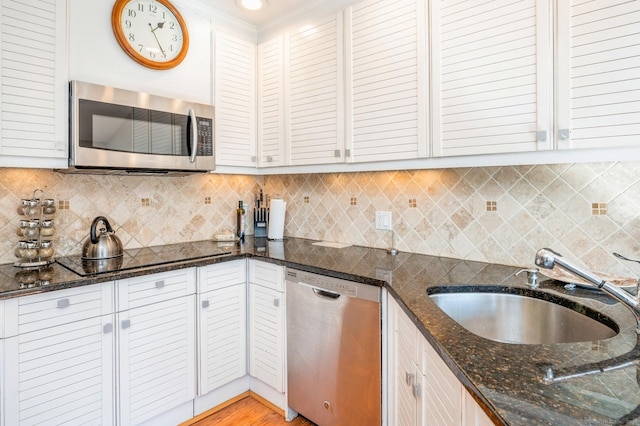 90 Akbar Rd, Stamford, CT 06902 - kitchen with appliances with stainless steel finishes, a sink, backsplash, dark stone counters, and white cabinetry