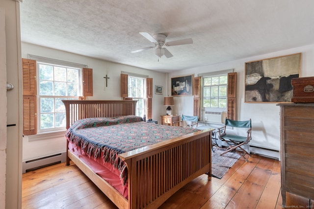 80 W Main St, Chester, CT 06412 - bedroom with baseboard heating, multiple windows, hardwood / wood-style flooring, a textured ceiling, and a ceiling fan