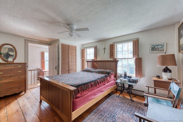 80 W Main St, Chester, CT 06412 - bedroom with wood-type flooring, a closet, a textured ceiling, a ceiling fan, and a baseboard radiator