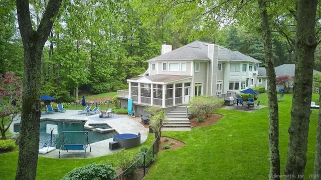 15 Arrowhead Way, Weston, CT 06883 - rear view of house featuring a sunroom, a patio area, a chimney, a pool with connected hot tub, and a shingled roof