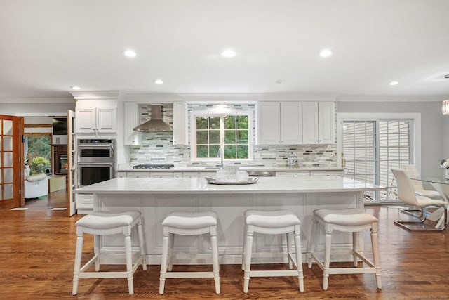 22 Fox Run, Wilton, CT 06897 - kitchen featuring wall chimney range hood, stainless steel double oven, ornamental molding, tasteful backsplash, and white cabinetry