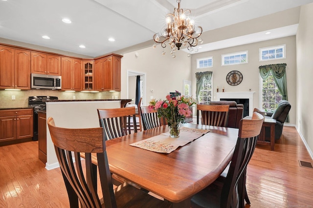 49 Bannan Ln Unit 49, Berlin, CT 06037 - dining room with light wood-type flooring, recessed lighting, a fireplace, a chandelier, and a towering ceiling