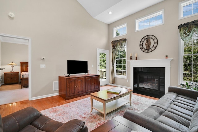 49 Bannan Ln Unit 49, Berlin, CT 06037 - living room featuring high vaulted ceiling, light wood-style floors, baseboards, healthy amount of natural light, and a fireplace with flush hearth