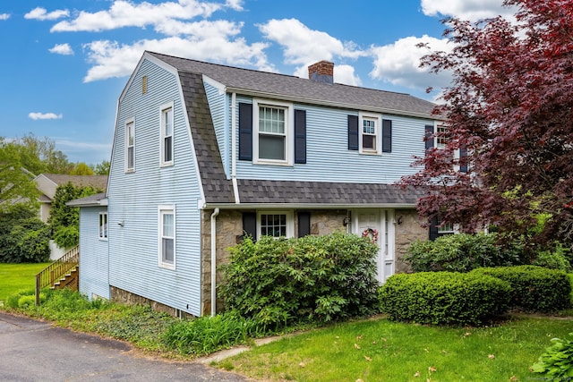 150 N Main St, Plymouth, CT 06786 - view of front facade featuring a chimney, stone siding, a gambrel roof, a shingled roof, and a front yard