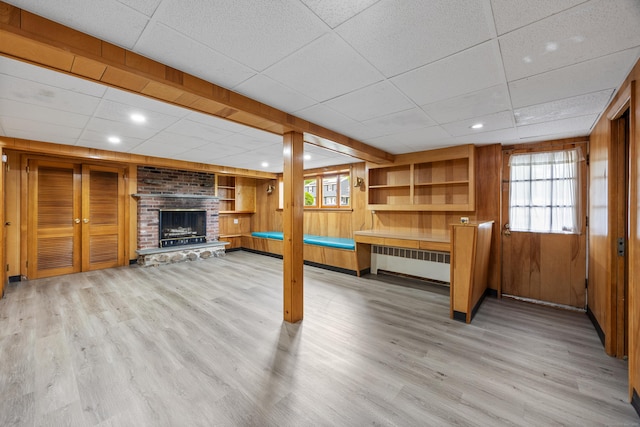 27 Hickory St, Plymouth, CT 06786 - below grade area with radiator heating unit, a paneled ceiling, wood walls, wood finished floors, and a brick fireplace