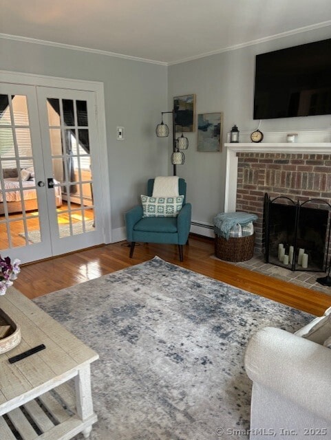 living room featuring ornamental molding, wood finished floors, french doors, a baseboard heating unit, and a fireplace