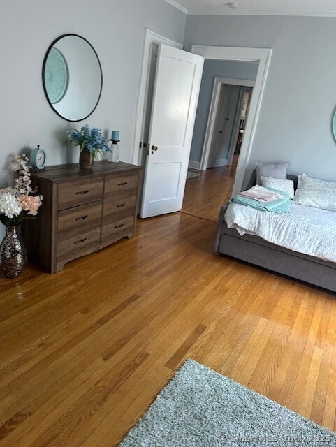 bedroom featuring ornamental molding and light wood finished floors