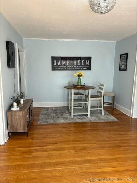 dining space featuring crown molding, wood finished floors, and baseboards
