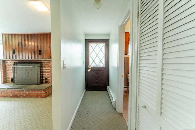 doorway with baseboard heating, carpet floors, baseboards, and a textured ceiling