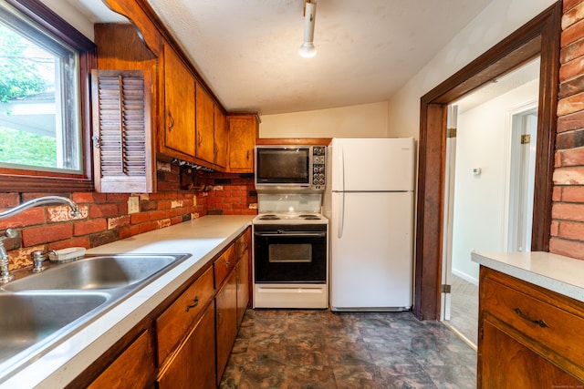 kitchen featuring freestanding refrigerator, range with electric cooktop, stainless steel microwave, a sink, and brown cabinets