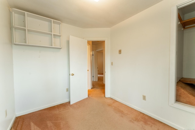 unfurnished bedroom featuring light colored carpet and baseboards