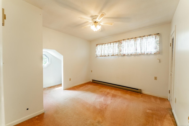spare room with a baseboard radiator, ceiling fan, carpet floors, and baseboards