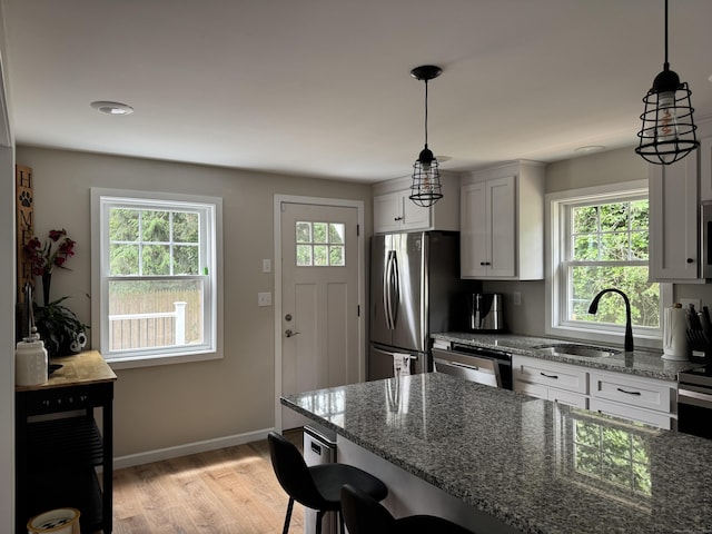 14 Russell St, Hamden, CT 06517 - kitchen featuring a breakfast bar, light wood-style flooring, dark stone counters, appliances with stainless steel finishes, and pendant lighting