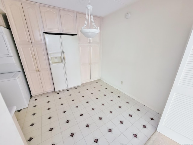 143 Hoyt St Apt 1F, Stamford, CT 06905 - kitchen featuring white fridge with ice dispenser, stacked washing machine and dryer, pendant lighting, and baseboards