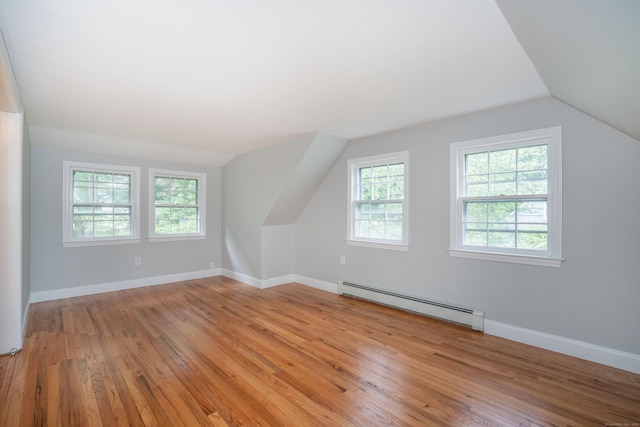 additional living space with baseboard heating, lofted ceiling, light wood-type flooring, and baseboards