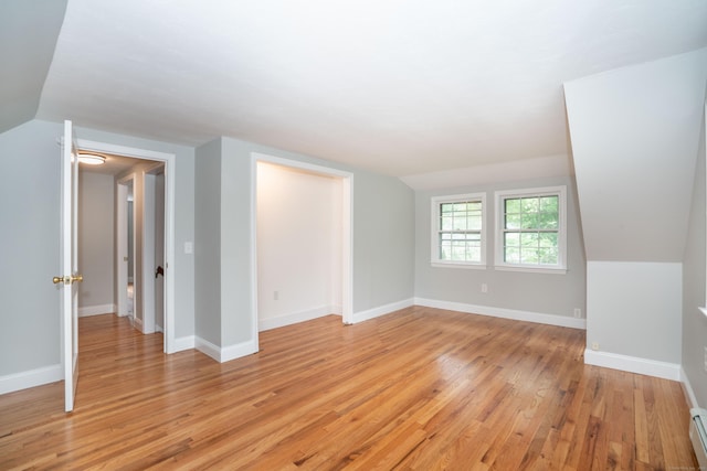 additional living space featuring lofted ceiling, light wood-style flooring, a baseboard radiator, and baseboards