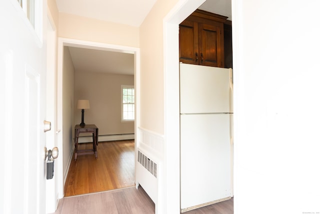 kitchen with freestanding refrigerator, radiator heating unit, and light wood-style flooring