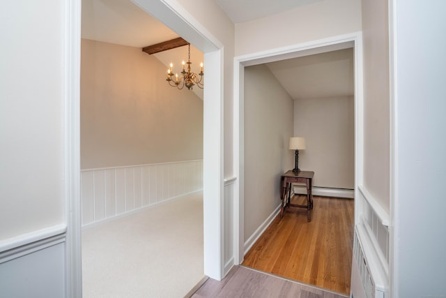 corridor featuring a chandelier, a baseboard heating unit, wood finished floors, and beam ceiling