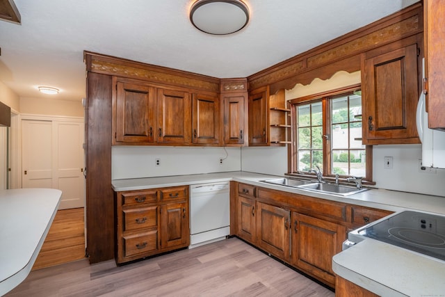 kitchen with a sink, dishwasher, brown cabinets, light wood-style floors, and light countertops