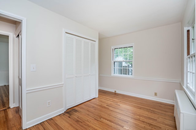 unfurnished bedroom with light wood-style floors, a closet, and baseboards