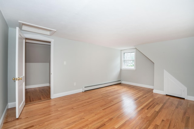 bonus room featuring a baseboard heating unit, attic access, light wood-style floors, and baseboards