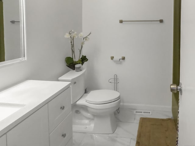 half bathroom featuring toilet, vanity, marble finish floors, and baseboards