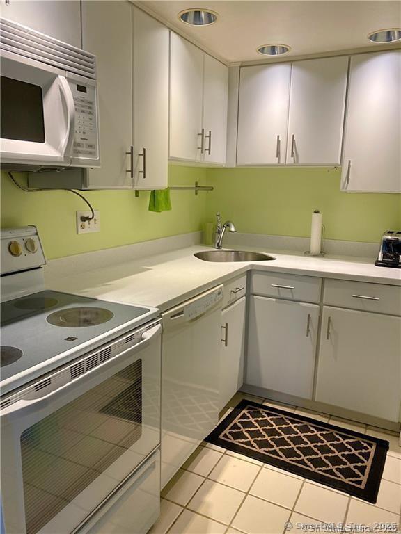 60 Strawberry Hill Ave Unit 1118, Stamford, CT 06902 - kitchen with white appliances, a sink, light countertops, light tile patterned flooring, and white cabinets