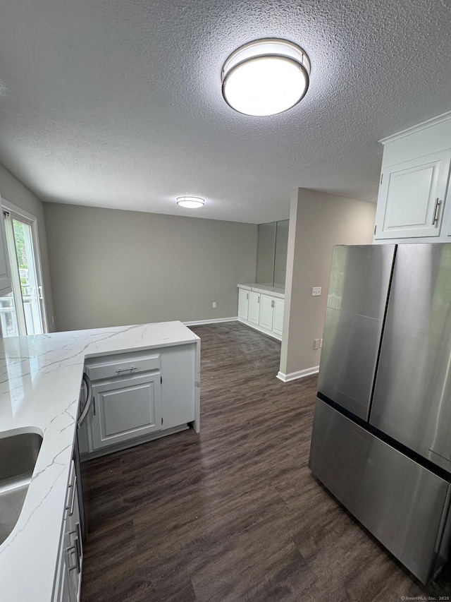 222 W Main St Apt 1C, Southington, CT 06479 - kitchen with freestanding refrigerator, a textured ceiling, dark wood finished floors, light stone countertops, and white cabinets