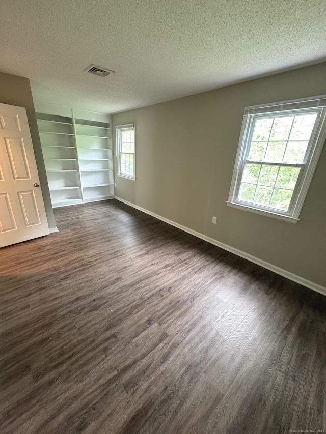 222 W Main St Apt 1C, Southington, CT 06479 - unfurnished room featuring dark wood-style flooring, a textured ceiling, baseboards, and built in features