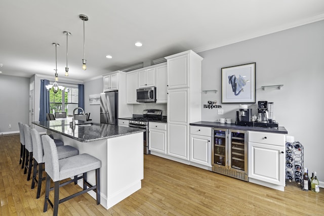 81 Tucker St Unit 81, Danbury, CT 06810 - kitchen with beverage cooler, stainless steel appliances, light wood finished floors, white cabinets, and a kitchen bar