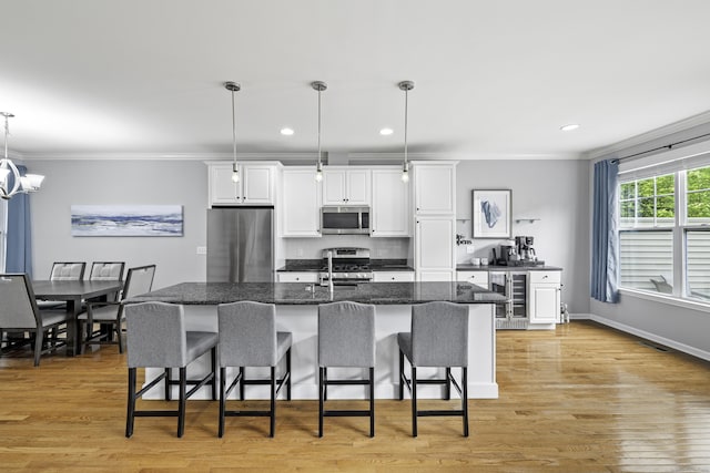 81 Tucker St Unit 81, Danbury, CT 06810 - kitchen with stainless steel appliances, ornamental molding, a breakfast bar, beverage cooler, and white cabinets